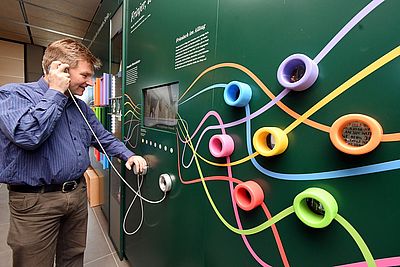 Ein Mann hört sich über einen Hörer in einem Museum Nordfriesisch an.