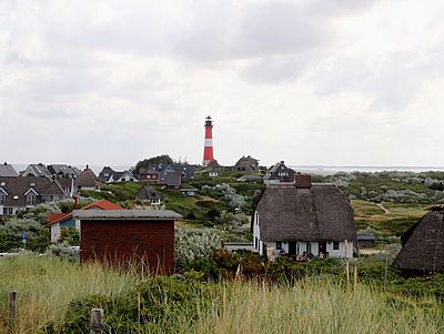 Der rot-weiß gestreifte Hörnumer Leuchtturm ragt hinter dem Dorf empor