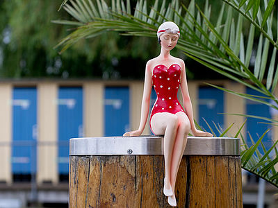 Figur einer Frau sitzt auf einem Holzpfahl