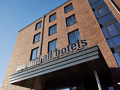 Außenaufnahme des Me an All Hotels Kiel mit Blick von unten hoch zu dem Schriftzug des Hotels und einigen Fenstern.