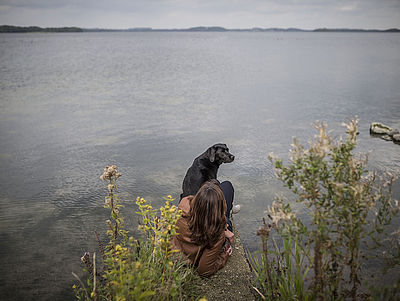Frau mit Hund am Ufer eines Sees