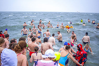Mehrere Menschen gehen beim Anbaden ins Wasser