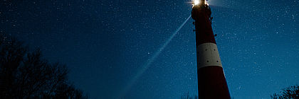 Leuchtturm vorm Sternenhimmel - zum Artikel 'Auf Pellworm Sterne gucken: Wo der Nachthimmel seine volle Pracht entfaltet'