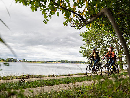 Zwei junge Frauen fahren mit ihren Fahrrädern entlang der Schlei.