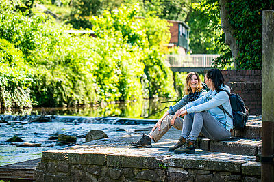 Zwei Frauen sitzen am Fluss