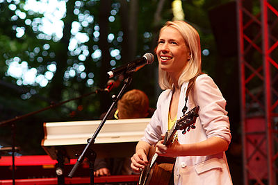 Eine junge Frau aus Föhr musiziert auf einer Bühne mit ihrer Gitarre.