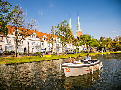 Familie fährt mit dem Boot mit Blick auf den Malerwinkel in Lübeck.